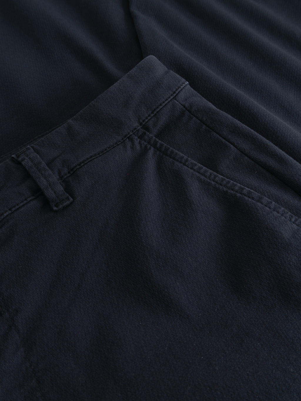 Close-up of the Gabba GABpaul K3280 Dale Chino in Blue Black, highlighting waistband, belt loop, French pockets, and stitching details, laid flat on a matching dark fabric background.