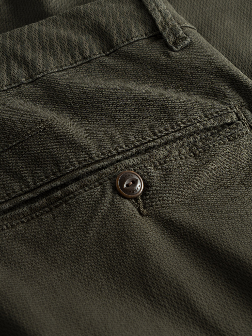 Close-up of the back pocket of the GABBA GABpaul K3280 Dale Chino - Army, showcasing textured olive green fabric, button closure, French pockets, and visible stitching for a modern look.