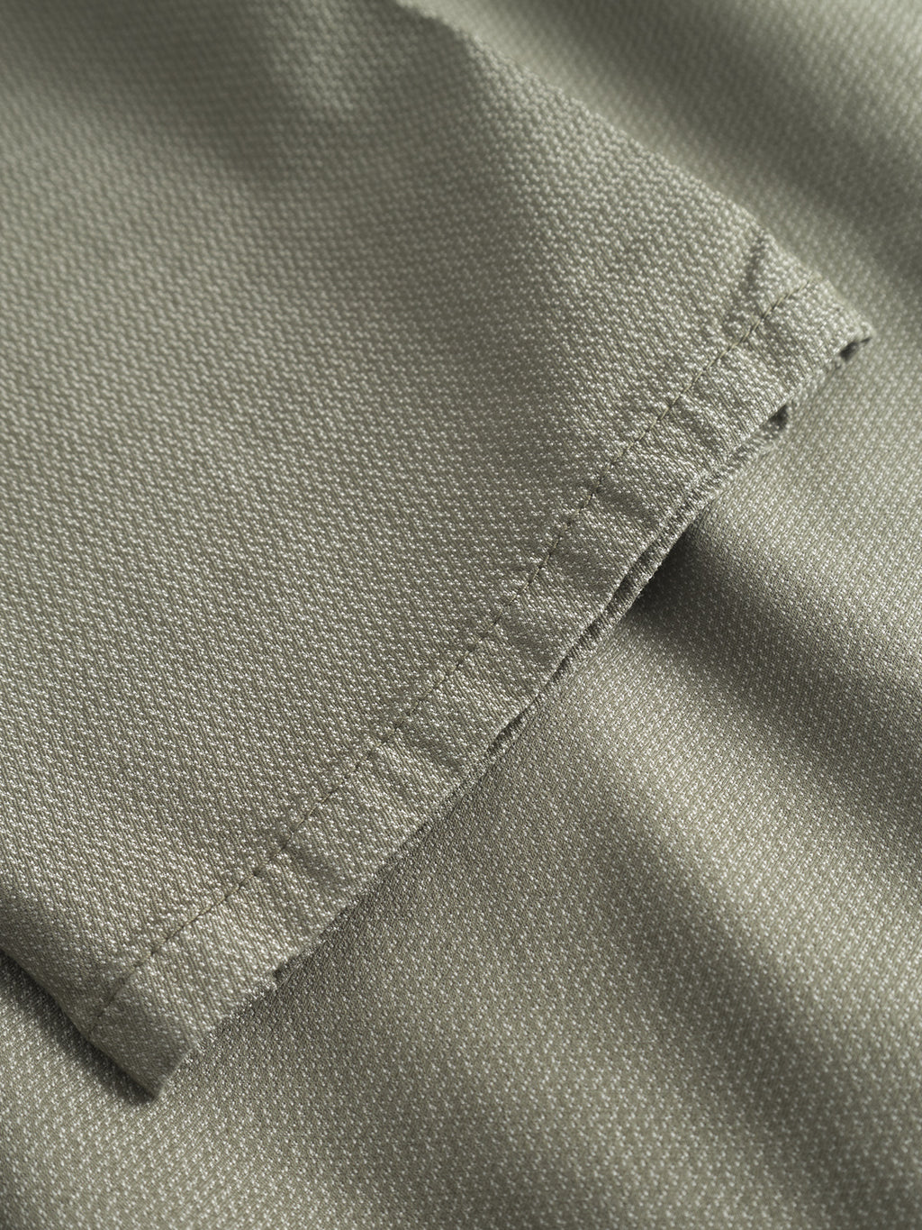Close-up of Gabba GABpaul K3280 Dale Chino in olive green, showing textured woven fabric, fine stitching on the hem, French pockets, and a slim leg opening.