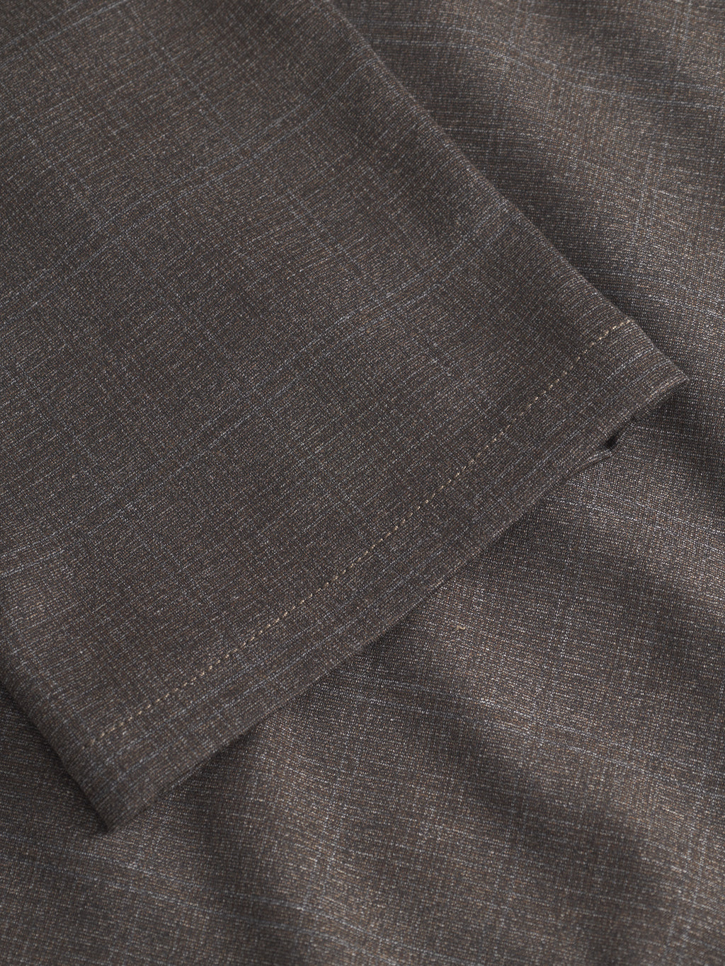 Close-up of GABpaul Nygo - Dark Brown comfort stretch fabric by Gabba, featuring a subtle plaid pattern and a visible stitched hem; showcases the fine texture and detailed weave—ideal for a versatile slim-fit chino.