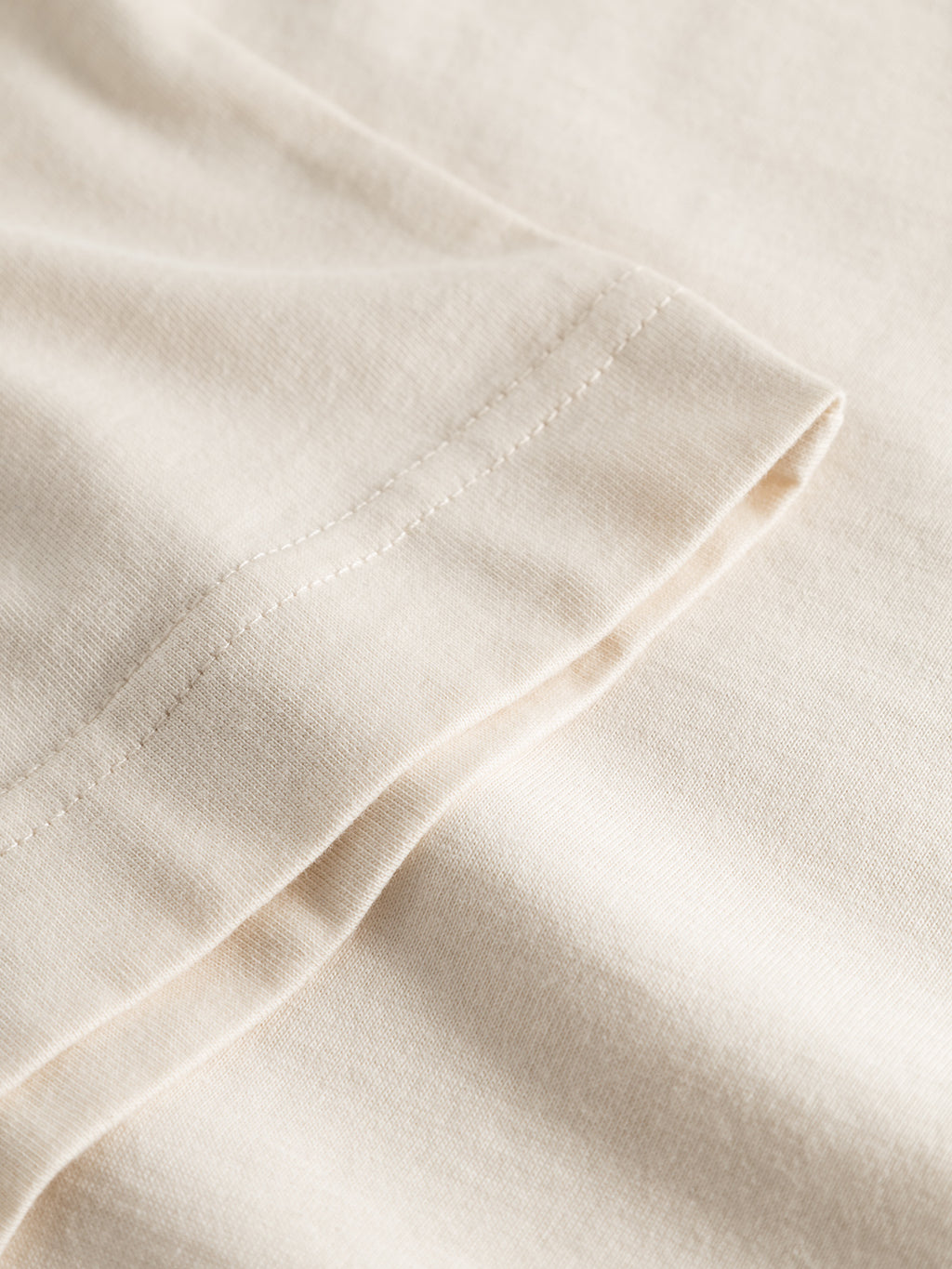 A close-up of the hem and stitching on the Gabba GABdune Logo GOTS SS T-Shirt in Birch, highlighting its fine texture and neat, straight seams.