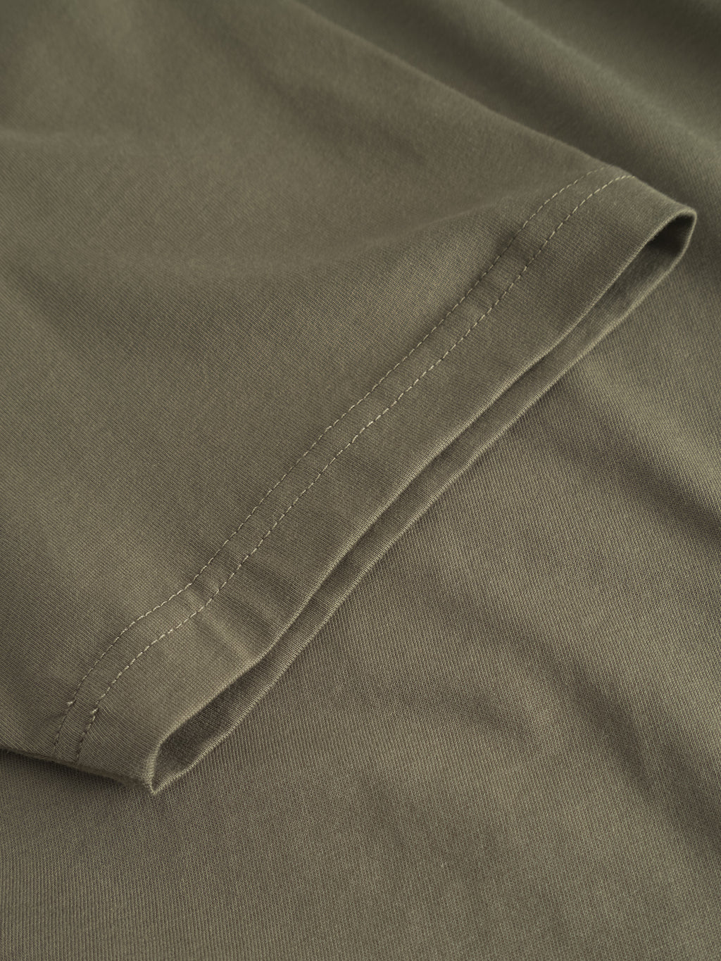 Close-up of the Gabba GABdune Logo GOTS SS T-Shirt in Deep Lichen Green, highlighting sleeve seam and stitching details against a matching fabric backdrop.