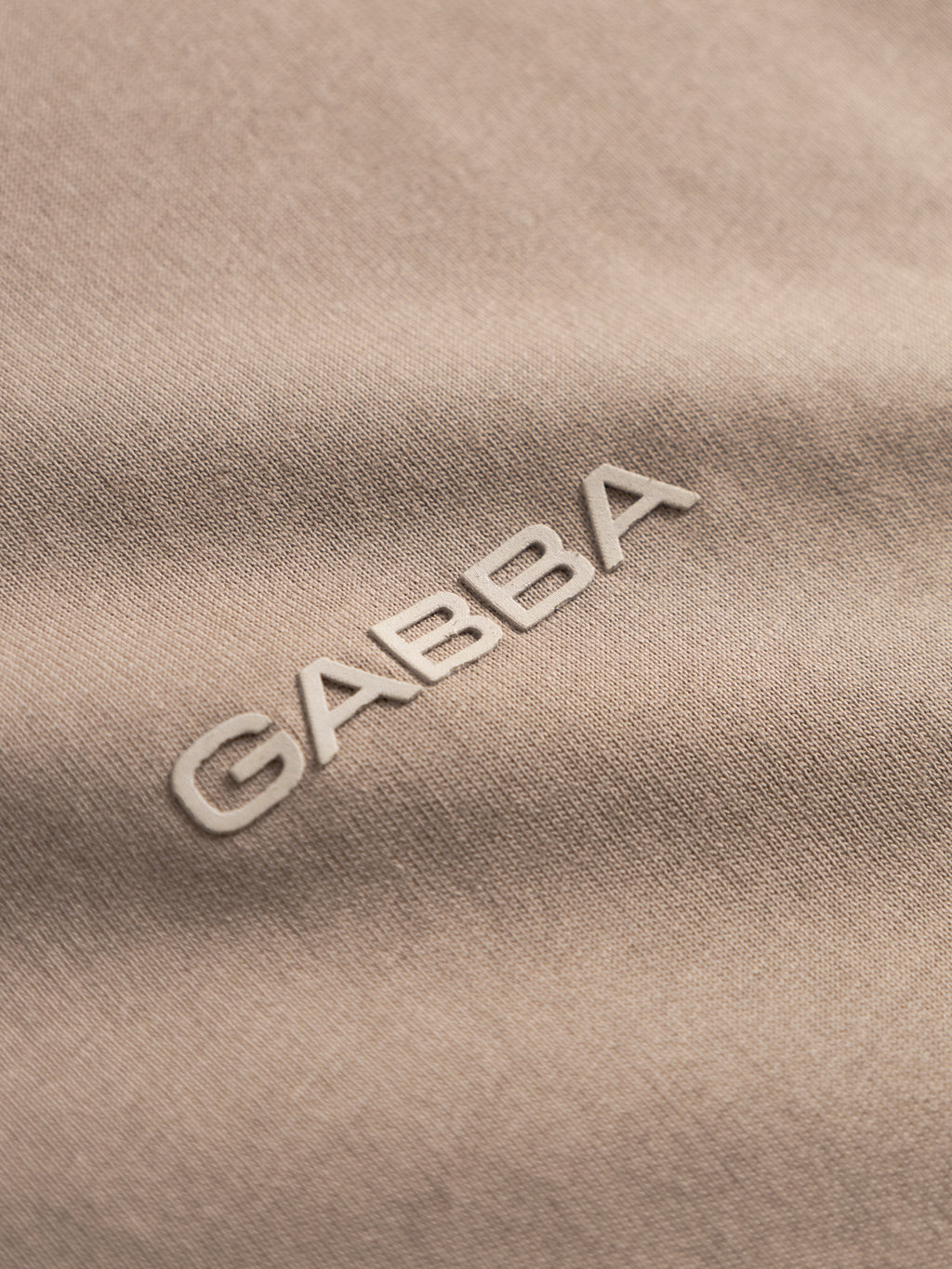 Close-up of beige fabric from the Gabba GABdune Logo GOTS SS T-Shirt - Fungi, showcasing raised white 