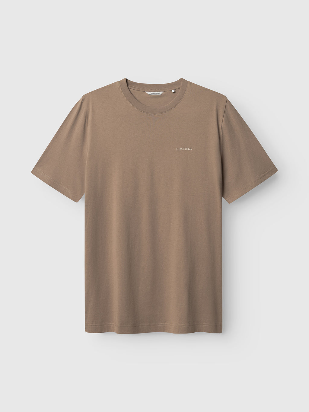 The Gabba GABdune Logo GOTS SS T-Shirt in Fungi is a plain, taupe organic cotton tee with short sleeves, a crew neckline, and a small white GABBA logo on the left chest, shown on a light gray background.