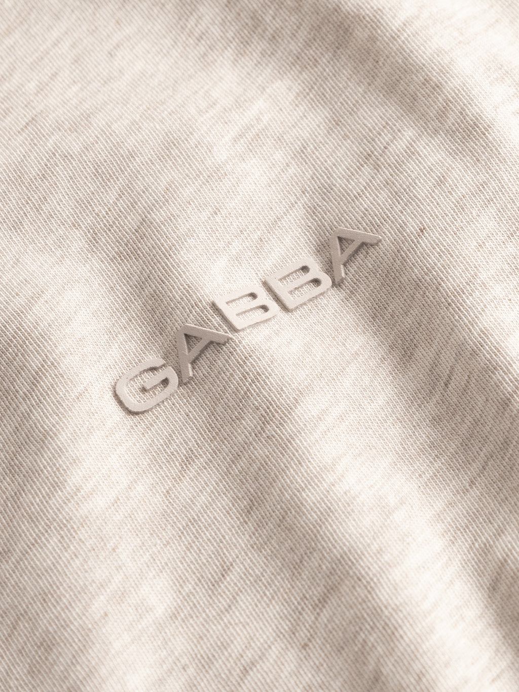 Close-up of the GABdune Melange New SS T-Shirt in Sand Mel. by Gabba, featuring a soft melange jersey texture and raised metallic Gabba logo.