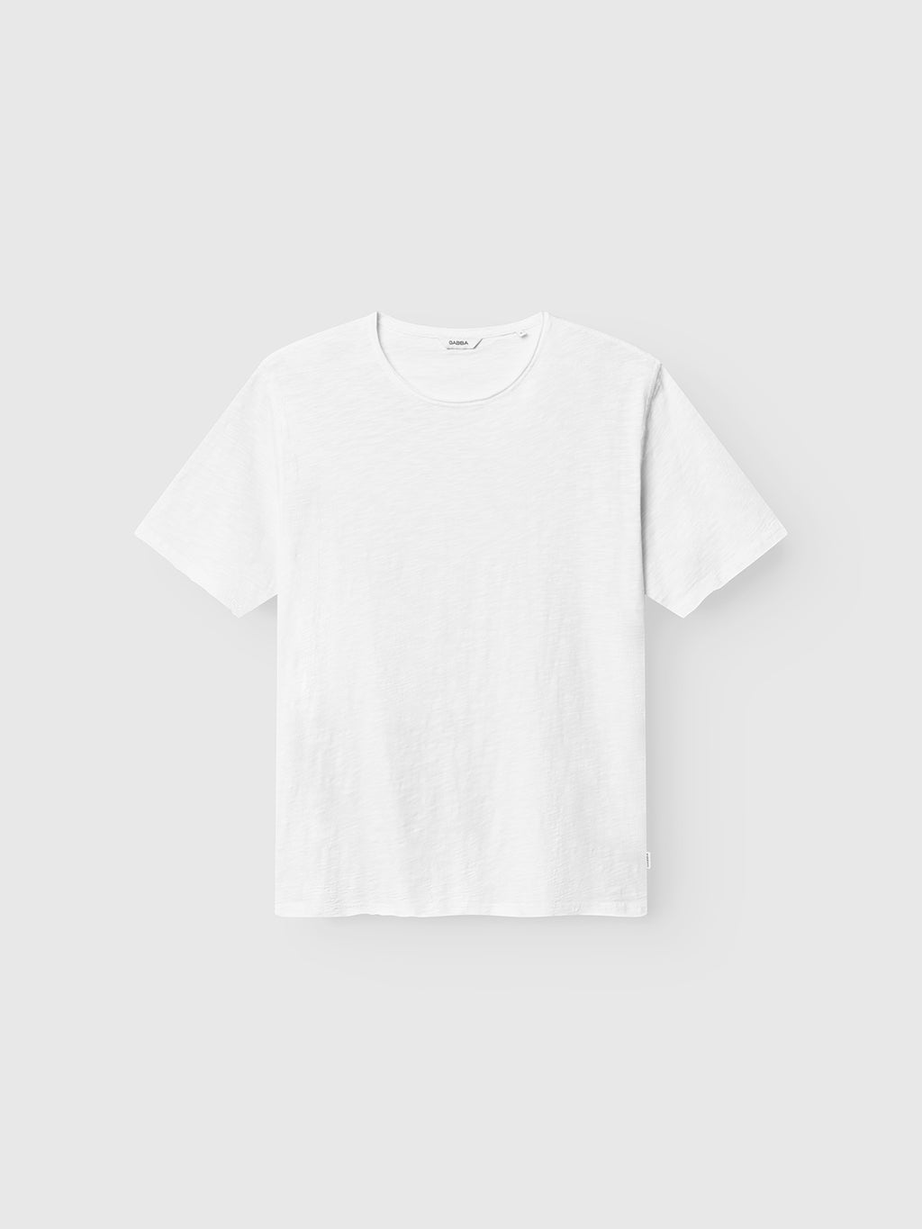 The Gabba GABkostant New SS - White is a plain, textured cotton short-sleeve t-shirt with a classic crew neck and relaxed fit, shown against a light gray background. Its design is simple and unadorned.