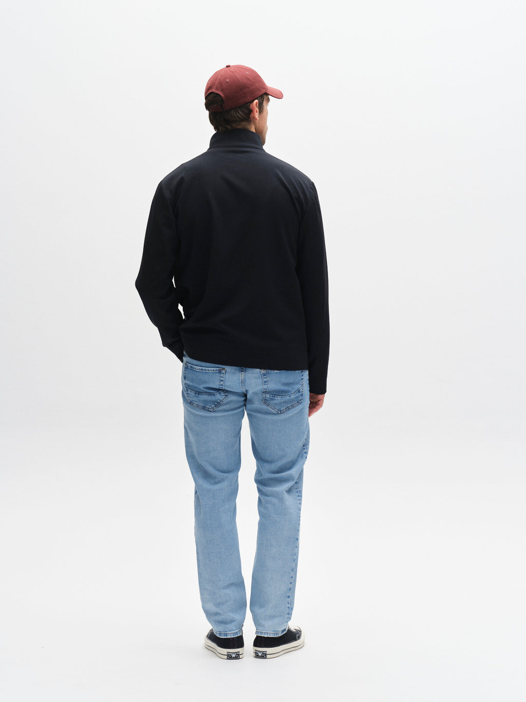 A person wearing a maroon cap, Gabba GABnik Phin GRS - Blue Black zip-through jacket, light blue jeans, and black sneakers stands facing away against a plain white background.