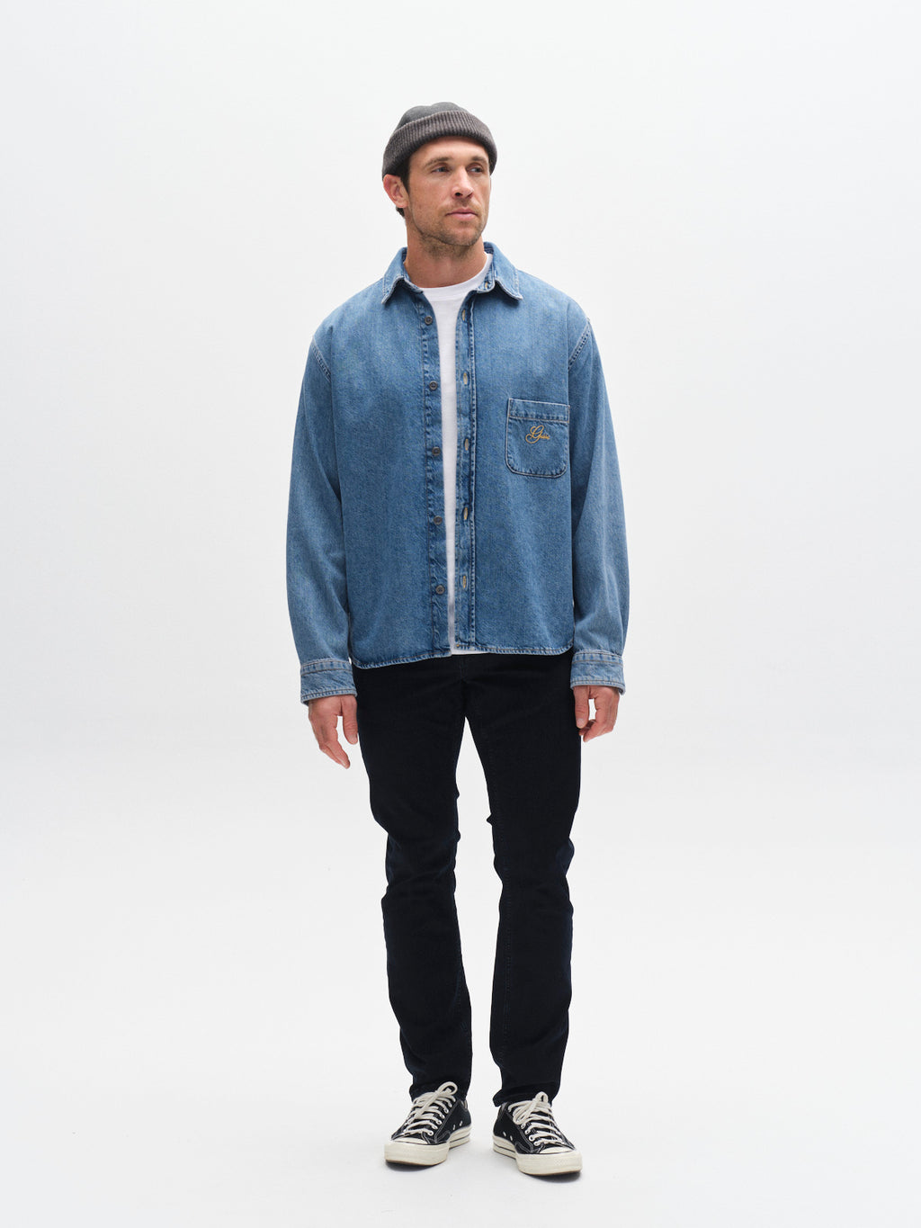 A man stands facing forward in a gray beanie, white tee, light blue shirt, Gabba GABjones BlueBlack - Blue Black Denim pants for all-day comfort and flexibility, and black sneakers against a plain white background.