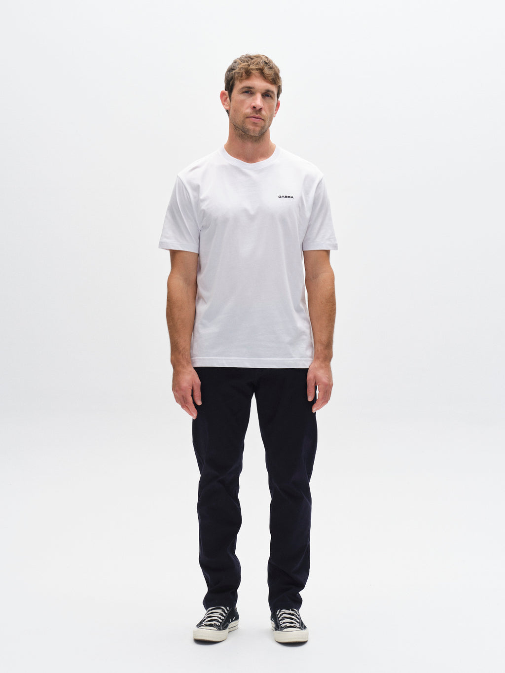 A man stands against a white background, wearing a white tee, black sneakers, and Gabba's GABmarc 5poc Marlo - Dark Navy jeans with classic 5-pocket styling. He looks to the side with a neutral expression—ideal for everyday wear.