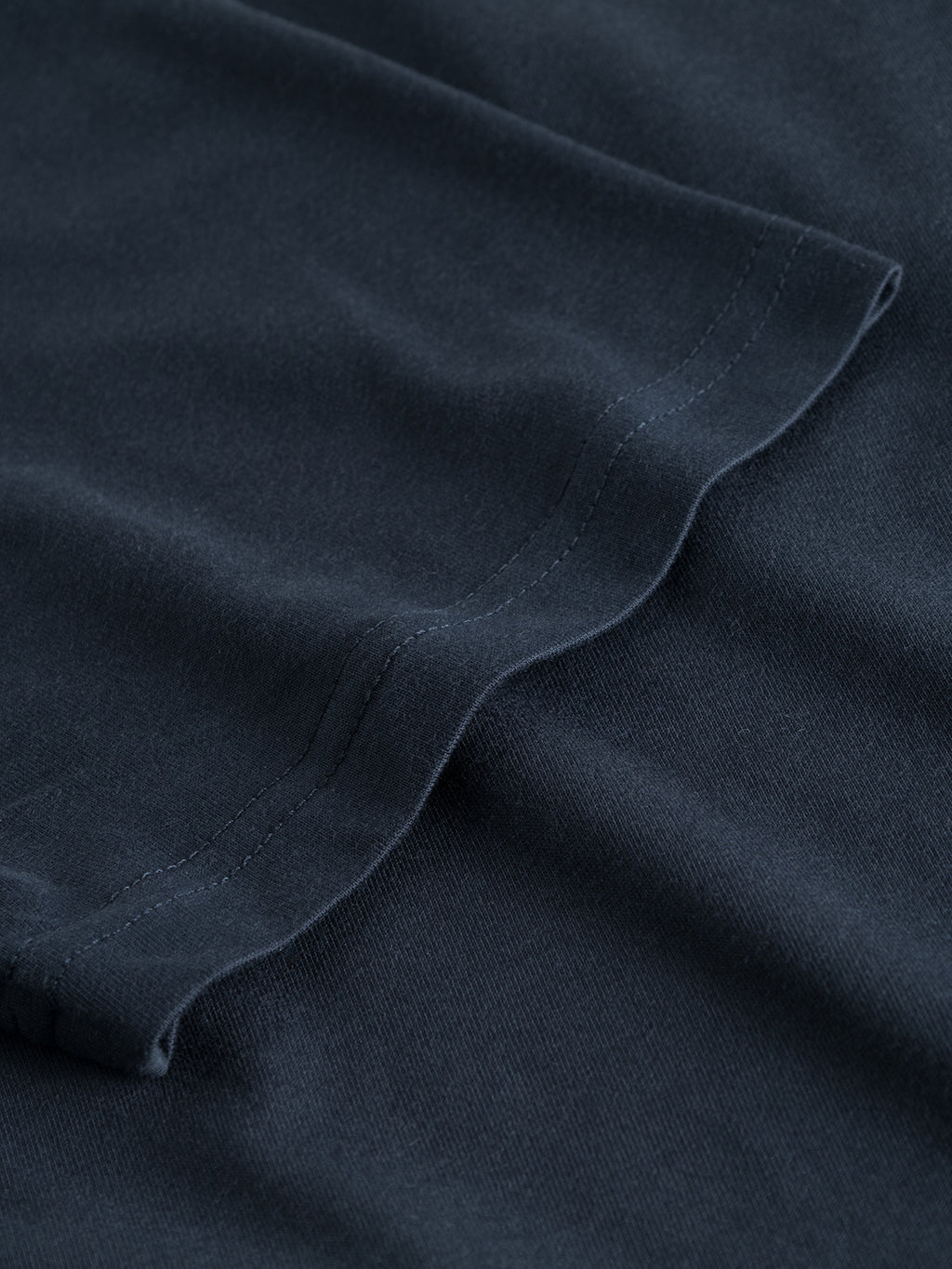 Close-up of the Gabba GABdune Logo GOTS SS T-Shirt in Total Eclipse, highlighting the smooth organic cotton texture, visible stitching along the hem, and neatly sewn edge.