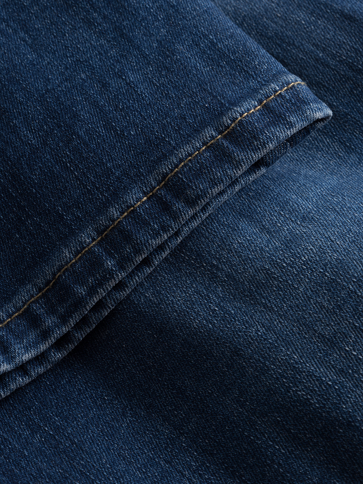 Close-up of Gabba GABjones K3870 Mid Blue Denim, highlighting the stitching and textured weave of super-stretch fabric. Overlapping edges and visible seam showcase the slim straight fit design.