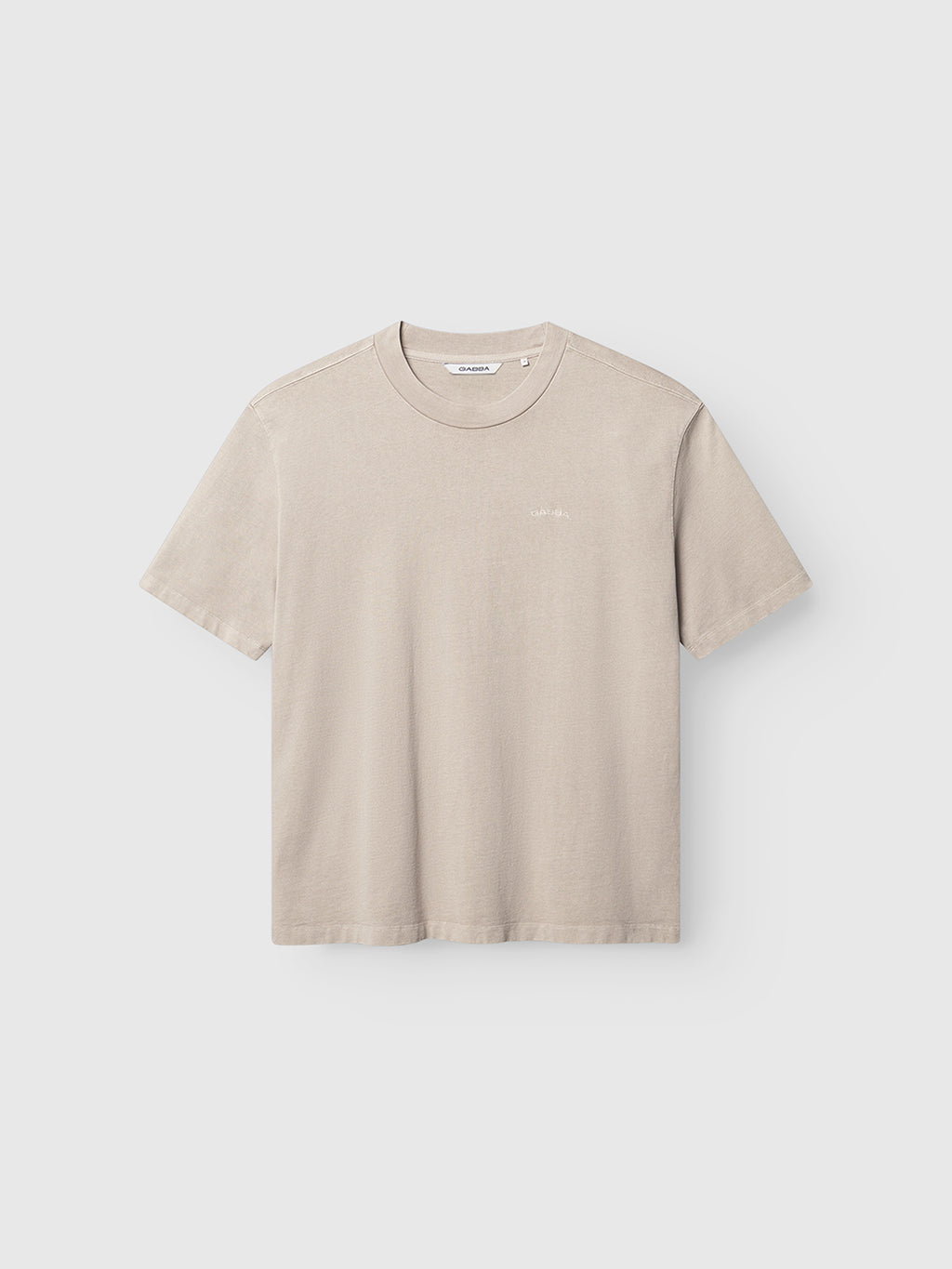 Gabba’s GABnigel Wix Boxy Hour SS in Sand Cashmere is shown on a plain white background. This beige short-sleeve t-shirt features a crew neckline and a relaxed, boxy fit made from heavyweight cotton. It’s minimally detailed with a small, subtle logo on the left chest for an understated finish.