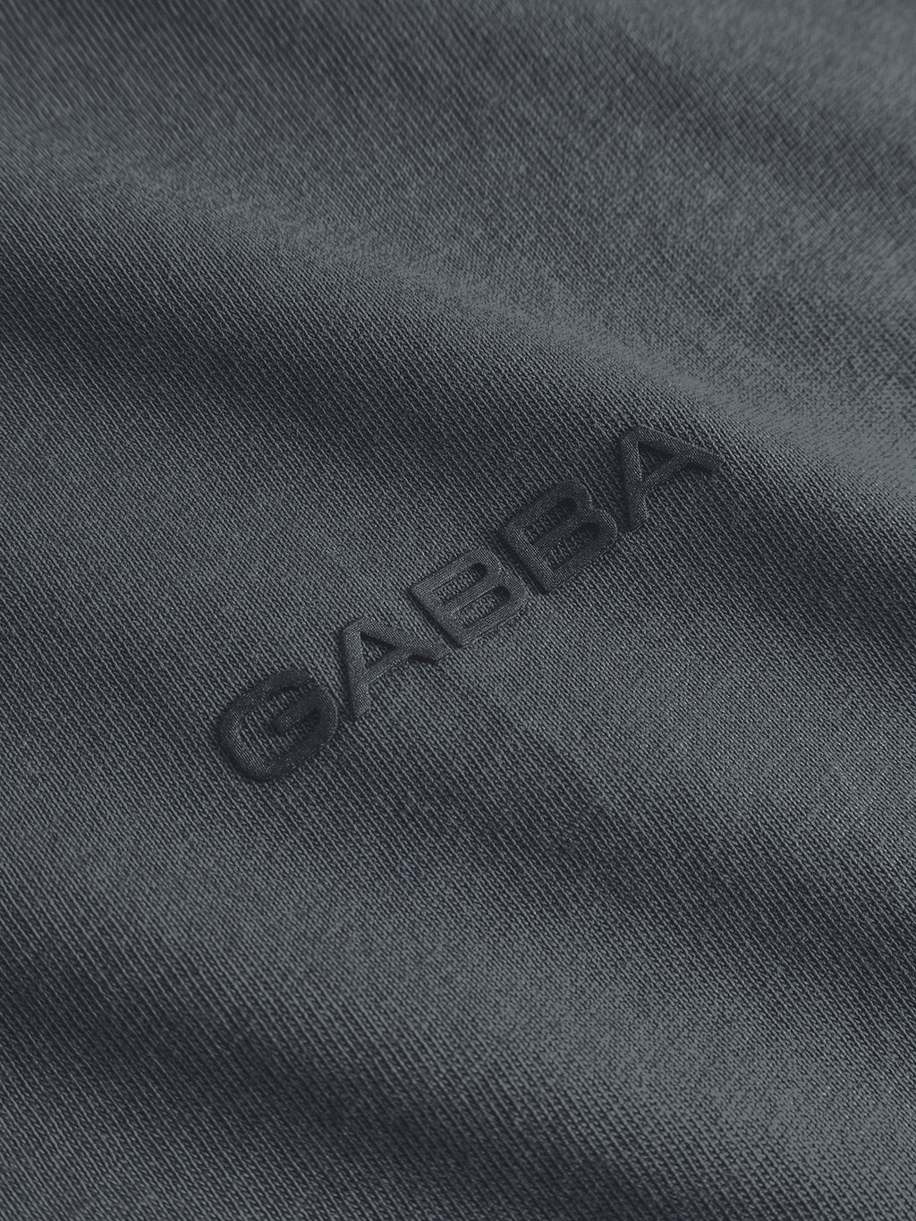 Close-up of the Turbulence Blue fabric from the GABdune Logo GOTS SS T-Shirt by Gabba, featuring “GABBA” subtly embroidered in matching thread for a textured, monochromatic finish.