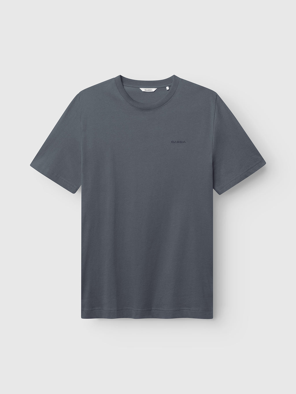 The Gabba GABdune Logo GOTS SS T-Shirt in Turbulence Blue is displayed against a light gray background. Made from GOTS-certified organic cotton, this classic fit tee features short sleeves, a classic crew neckline, and a small, subtle logo on the left chest.
