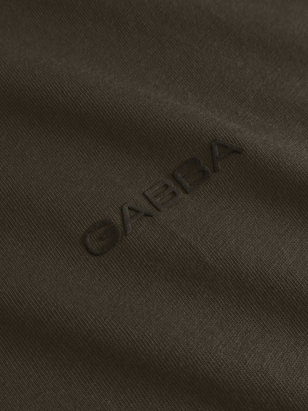 Close-up of the Forest Night GABdune Logo GOTS SS T-Shirt by Gabba, featuring dark olive green, silicone-washed fabric with “GABBA” embroidered in matching thread for a subtle, textured effect on this classic-fit tee.