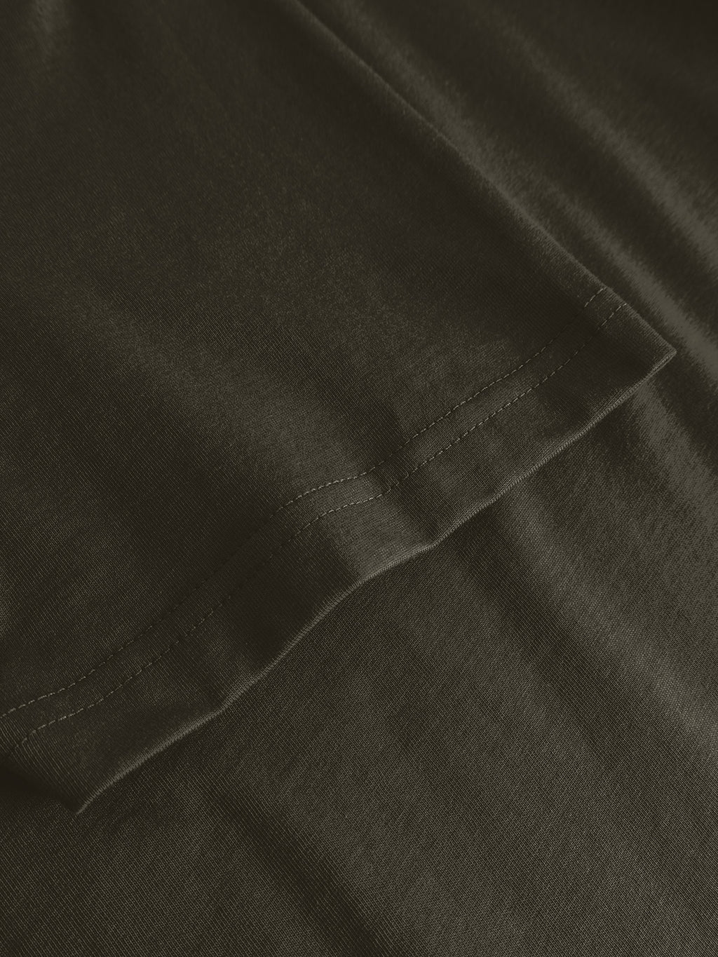 Close-up of the hem and stitching detail on the Gabba GABdune Logo GOTS SS T-Shirt in Forest Night, highlighting the organic cotton fabric texture and seam.