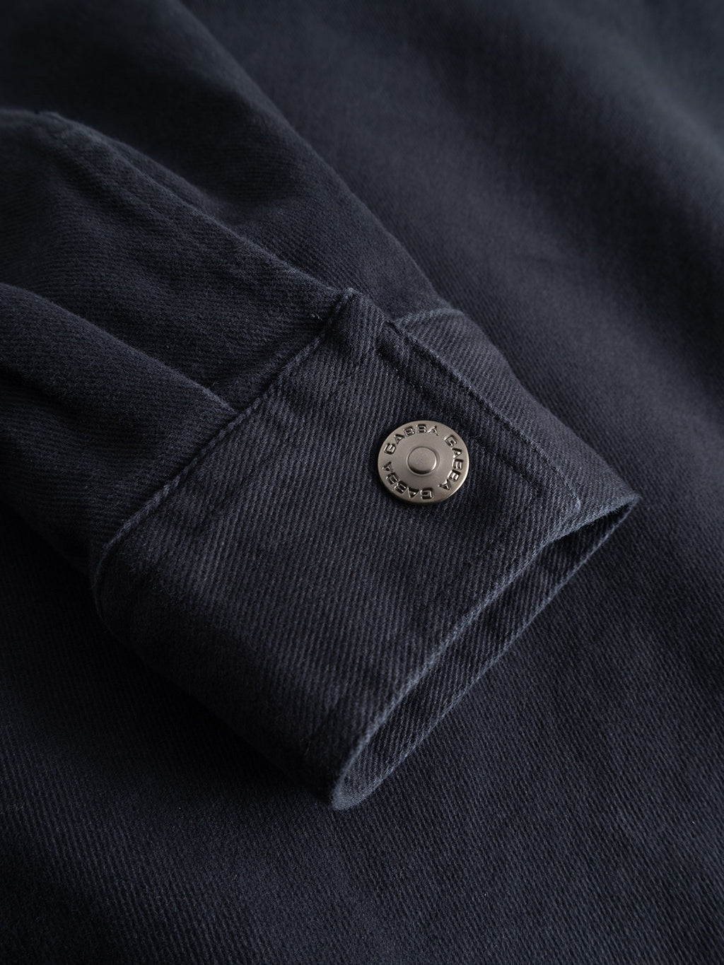 Close-up of a GABbeta Twill - Navy sleeve from Gabba, featuring a metal snap button on the cuff with visible stitching and rich fabric texture. Crafted from garment-dyed stretch twill, this piece delivers both comfort and style.