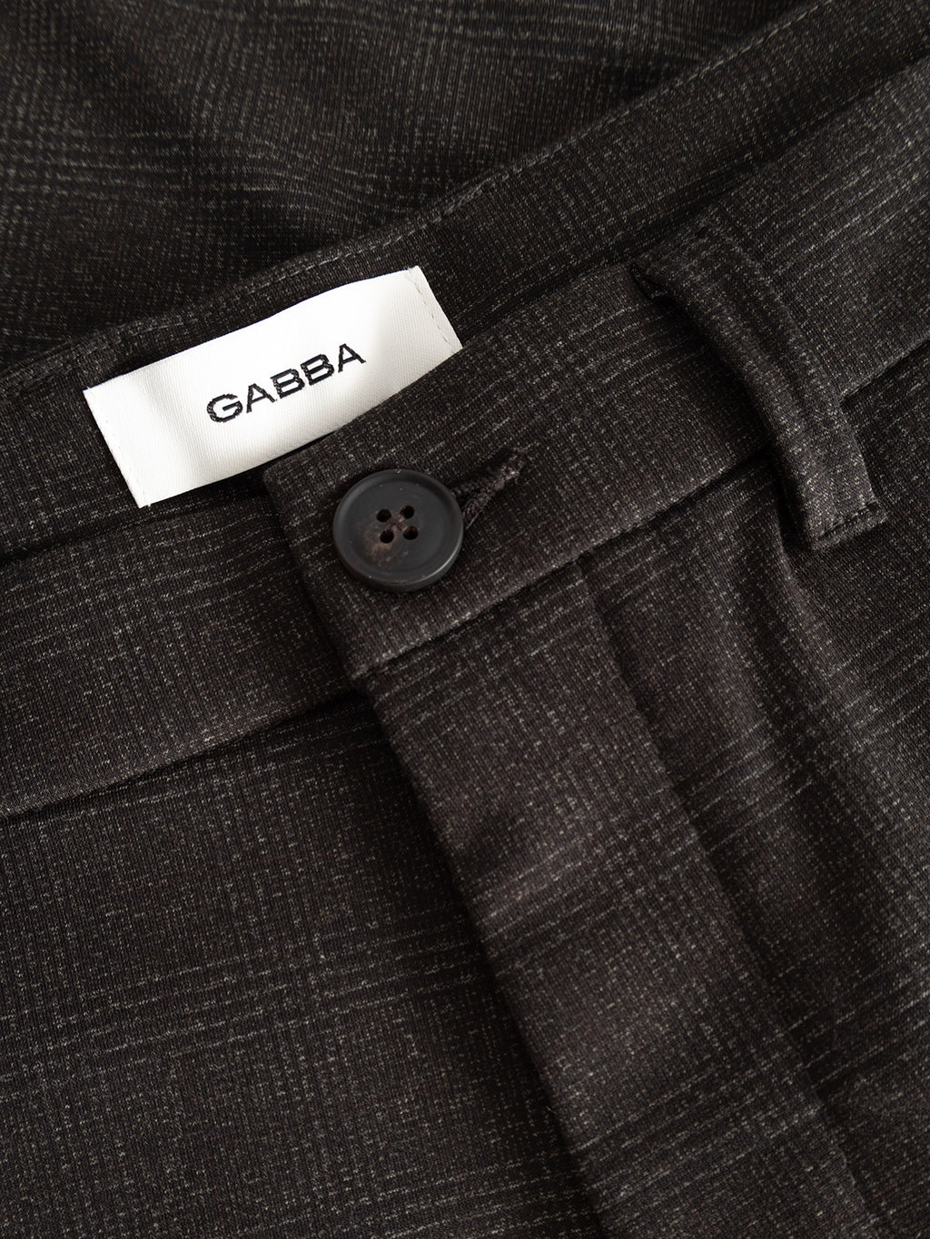 Close-up of the GABpaul Nygo - Brown Check pants, showcasing a button closure, belt loops, and a white Gabba brand label sewn into the waistband. Made from comfortable stretch fabric and tailored in a slim chino fit, these pants are ideal for everyday wear.