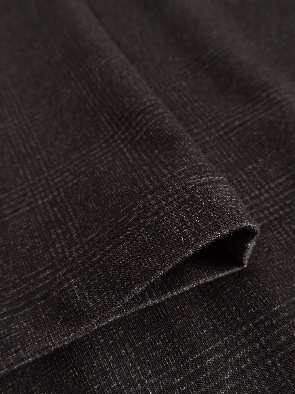 Close-up of folded GABpaul Nygo - Brown Check fabric by Gabba, featuring a subtle plaid pattern with fine intersecting lines—the comfort stretch material offers texture and flexibility, making it ideal for everyday wear.