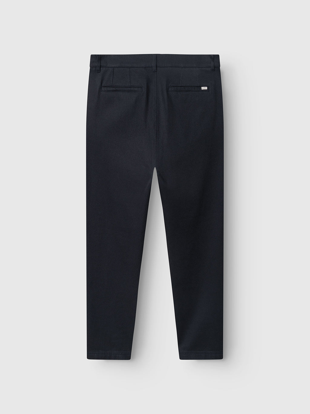 Back view of the Gabba GABJoe-Pas Vill trousers in blue black, utility-inspired with belt loops and two back pockets, crafted from drapey cotton twill, displayed against a plain light gray background.