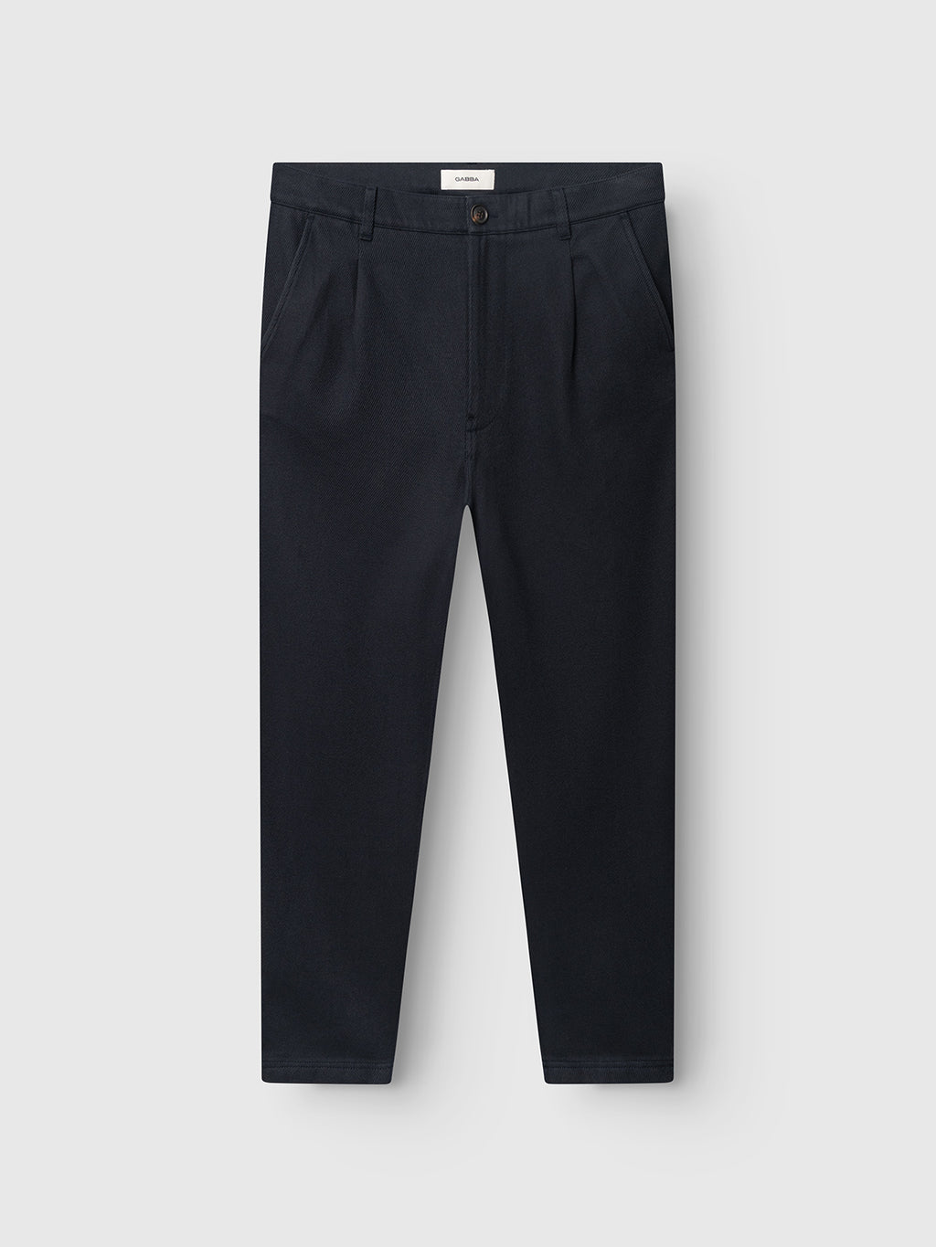 The Gabba GABJoe-Pas Vill - Blue Black trousers feature a utility-inspired design with front pleats, straight legs, side pockets, belt loops, and a button closure. Crafted from drapey cotton twill in a dark navy blue (blue black) shade, these neatly pressed trousers are displayed on a plain white background.