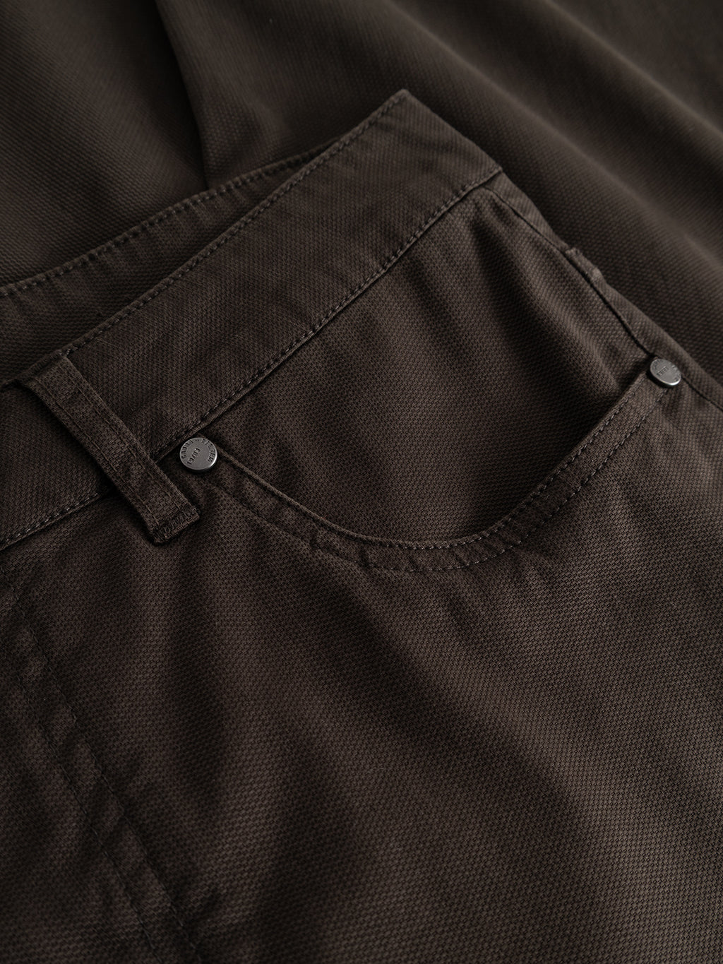 Close-up of the GABmarc 5poc Marlo - Brown Slate pants by Gabba, highlighting the textured brown fabric, visible stitching, belt loop, and twin rivets at the pocket corners—timeless details characteristic of everyday regular fit jeans.