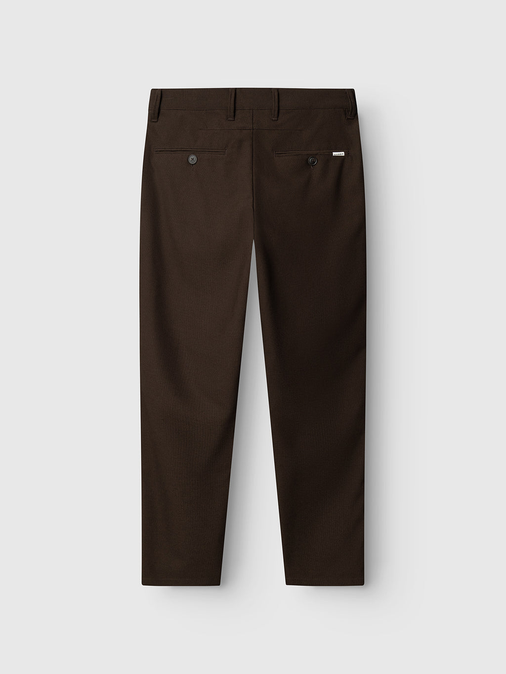 The GABpaul Deme Pant in Brown Slate by Gabba is displayed from the back against a plain light background, showcasing its slim chino fit and micro-pattern woven fabric. The pants feature two back pockets with button closures and a small Gabba brand tag above the right pocket.