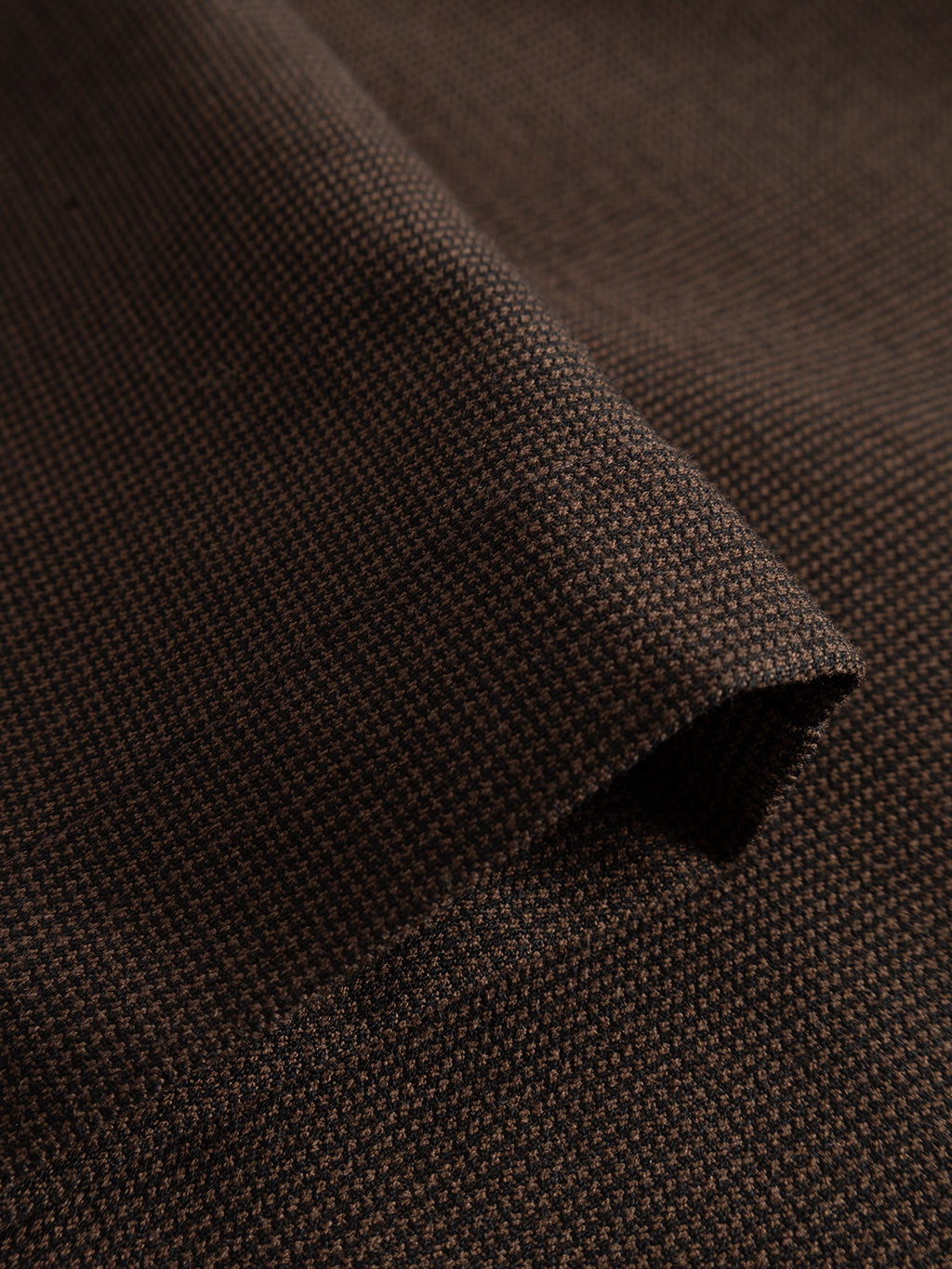 A close-up view of the brown slate micro-pattern woven fabric of Gabba’s GABpaul Deme Pant, highlighting its small grid texture, folded edge, and detailed weave—ideal for crafting a versatile chino or slim-fit pant.