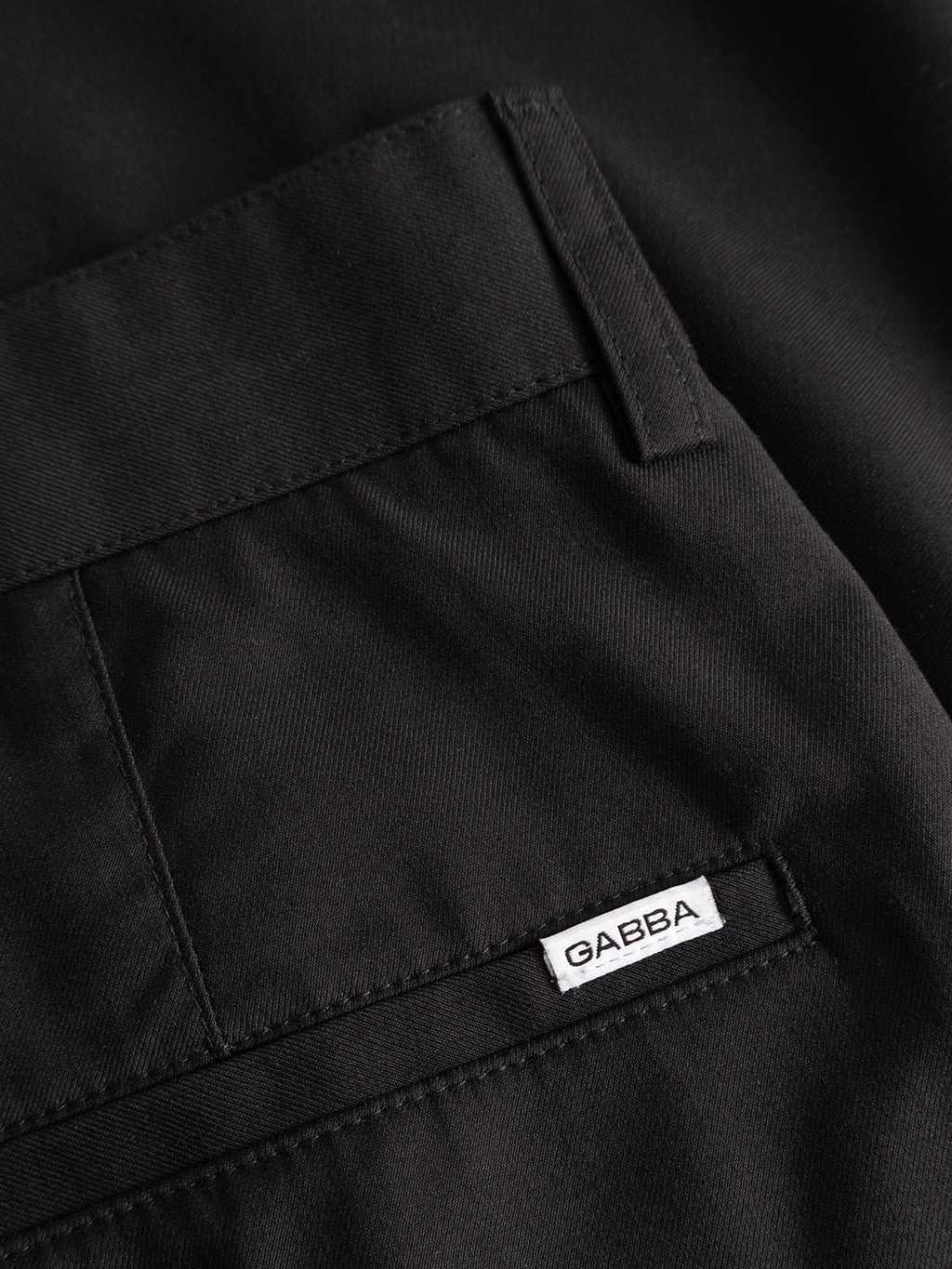 Close-up of the GABjoe Turnup Fin Pant in black by Gabba, featuring a classic chino pocket with a small white GABBA label sewn into the seam, smooth twill viscose blend fabric, and precise stitching.