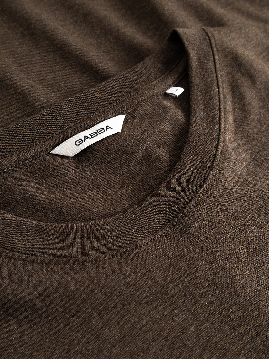 Close-up of the GABdune Melange New SS T-Shirt in Brown Slate, highlighting the collar and a white label featuring the Gabba brand and a small size tag marked S, crafted from soft melange jersey for enhanced comfort.