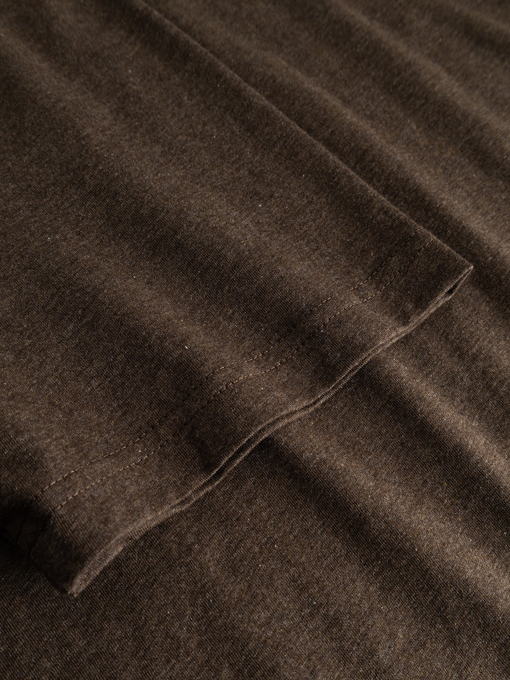 Close-up of the hem and sleeve of the Gabba GABdune Melange New SS T-Shirt in Brown Slate, highlighting the stitching detail and soft melange jersey texture against a flat background.