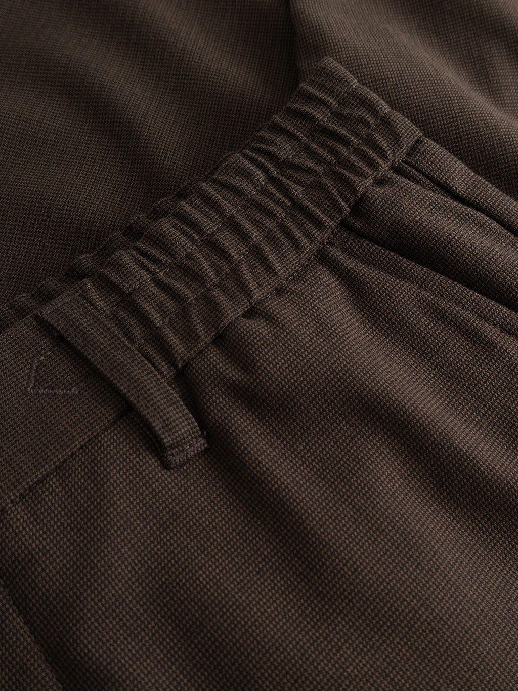 Close-up of the Gabba GABmonza Tasca Deme Pant in Brown Slate, featuring a dark brown micro-patterned fabric, elastic waistband with belt loops, and side pocket, designed in a relaxed straight fit.