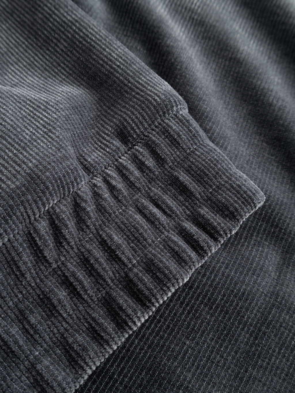 Close-up of the GABnik Pulz Fune Jacket by Gabba in Turbulence Blue, highlighting its textured gray corduroy jersey fabric with prominent vertical ridges and an area of gathered, elasticized stitching—exemplifying the refined detailing characteristic of modern Gabba outerwear.