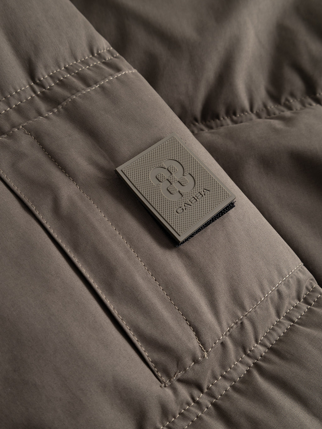 Brown GABjulien Calle Outerwear - Brown Slate padded insulation jacket with a rectangular rubberized logo patch on the chest and an adjustable hood.