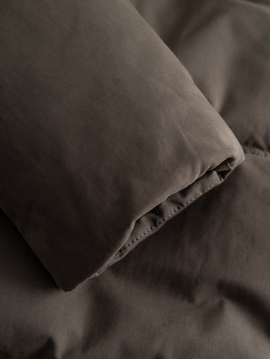 Close-up of a brown quilted sleeve from a GABjulien Calle Outerwear - Brown Slate puffer jacket.