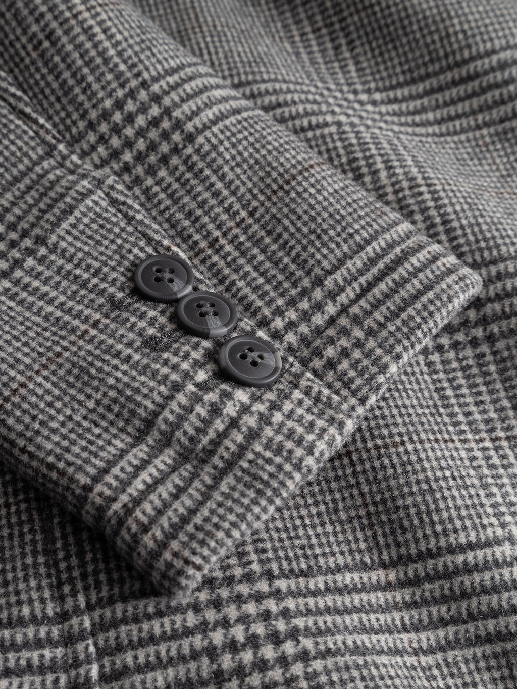 Close-up of the Gabba GABowen Scacco Coat in Grey Check, showing the wool-blend plaid fabric and three black buttons arranged vertically on the tailored blazer sleeve cuff.