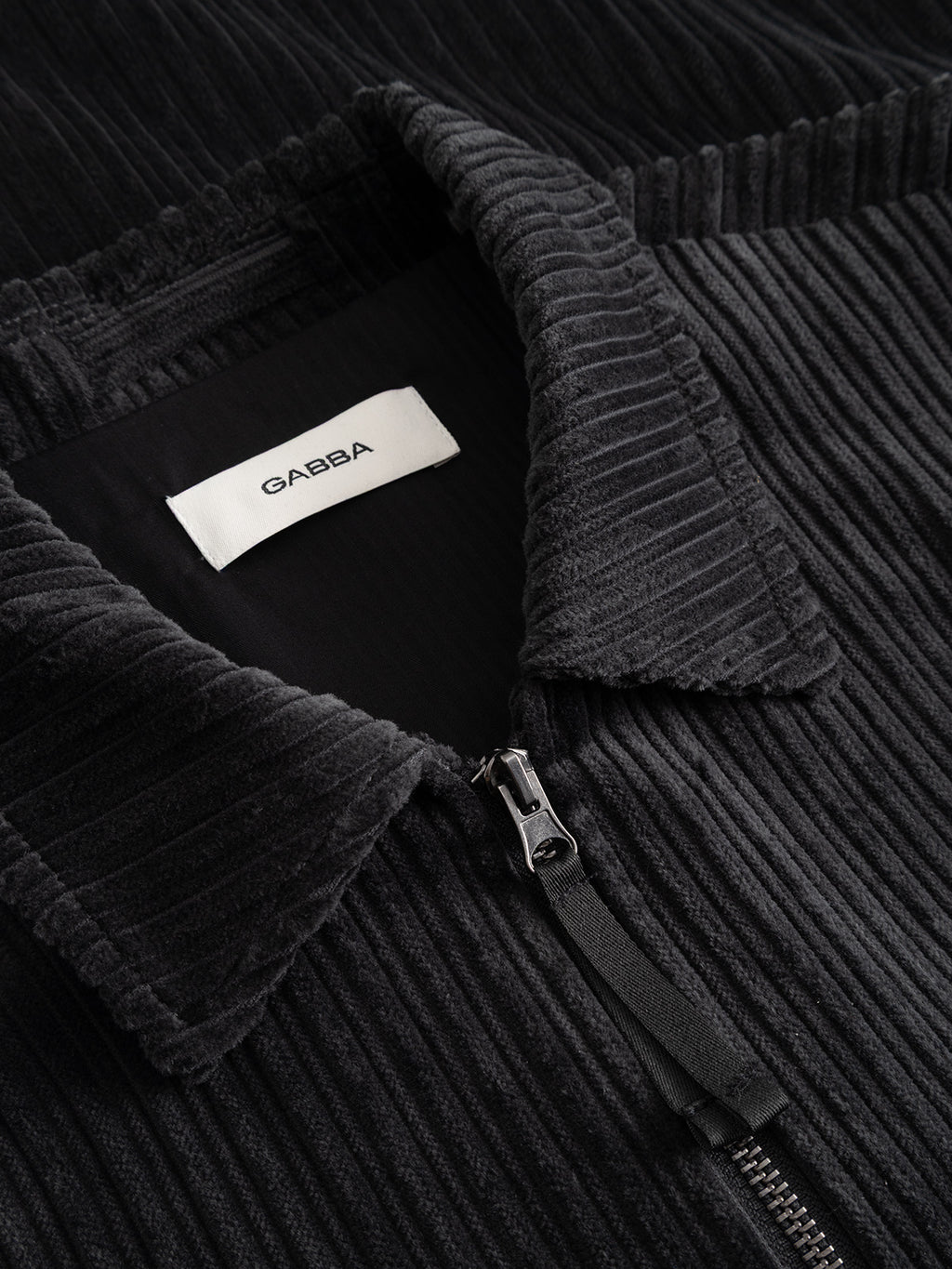 Close-up of the Gabba GABnik Zip Riglia GOTS Jacket in dark grey wide-wale corduroy, featuring a visible collar and an interior white label at the neckline with the brand name Gabba.
