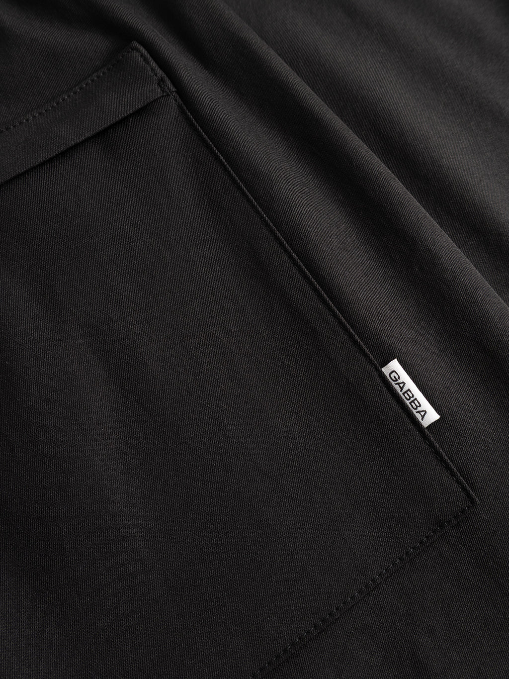 Close-up of a black fabric pocket on the GABzeta Nord Work Pant - Meteorite by Gabba, crafted from lightweight technical twill. A small white tag labeled “GABBA” is sewn into the seam, highlighting the workwear-inspired texture and detailed stitching.