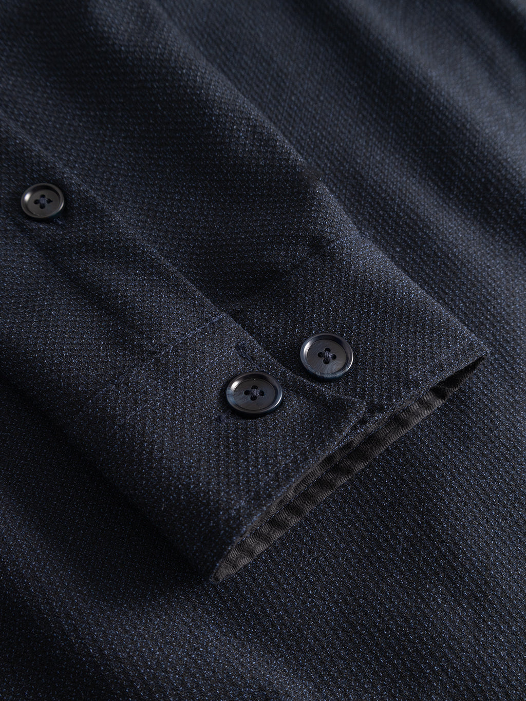 Close-up of the Gabba GABjens Over Rubin LS Overshirt in Blue Black, showcasing the dark navy blue cuff with a subtle textured pattern. Crafted from stretch dobby fabric, it features two black buttons for fastening. The soft, slightly reflective material enhances comfort and flexibility, making it ideal for an oversized fit.
