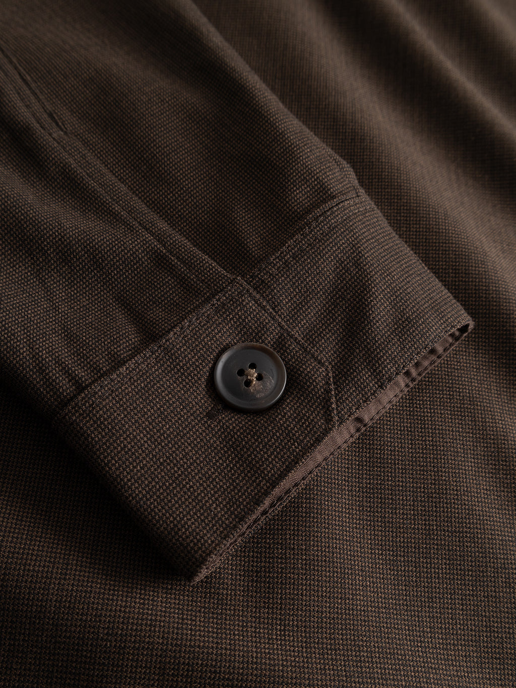A close-up of the Gabba GABtogger Base Deme LS Overshirt in Brown Slate, featuring a regular fit cuff with fine stitching, a small checkered micro-pattern woven fabric, and a single black button.