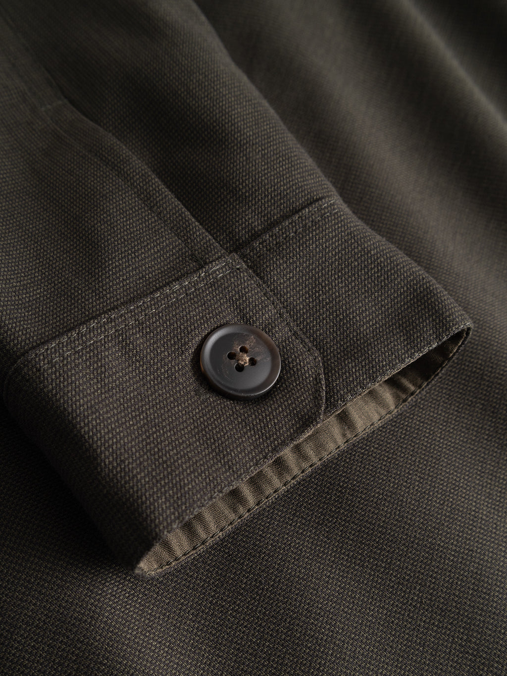 Close-up of the Gabba GABtogger Base Deme LS Overshirt in Forest Night, featuring a dark green micro-pattern woven fabric sleeve with a single black button and visible stitching detail.