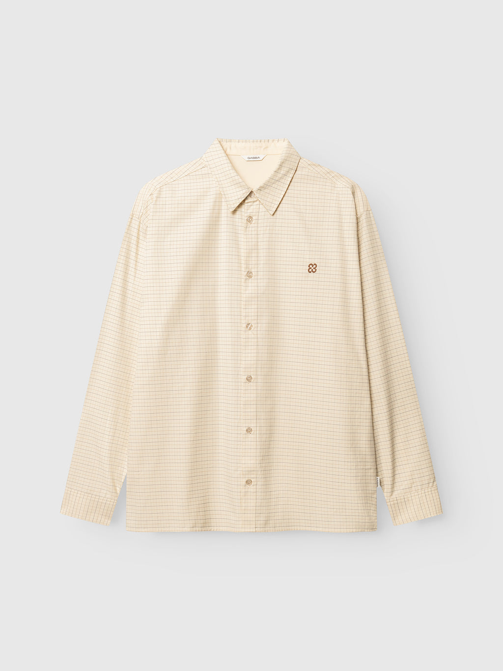 The Gabba GABjens Over Indie LS Shirt in Lt. Sand is a beige long-sleeve button-up shirt, crafted from a soft cotton-blend fabric featuring a subtle yarn-dyed checkered pattern and a small embroidered logo on the left chest, displayed on a plain light background.