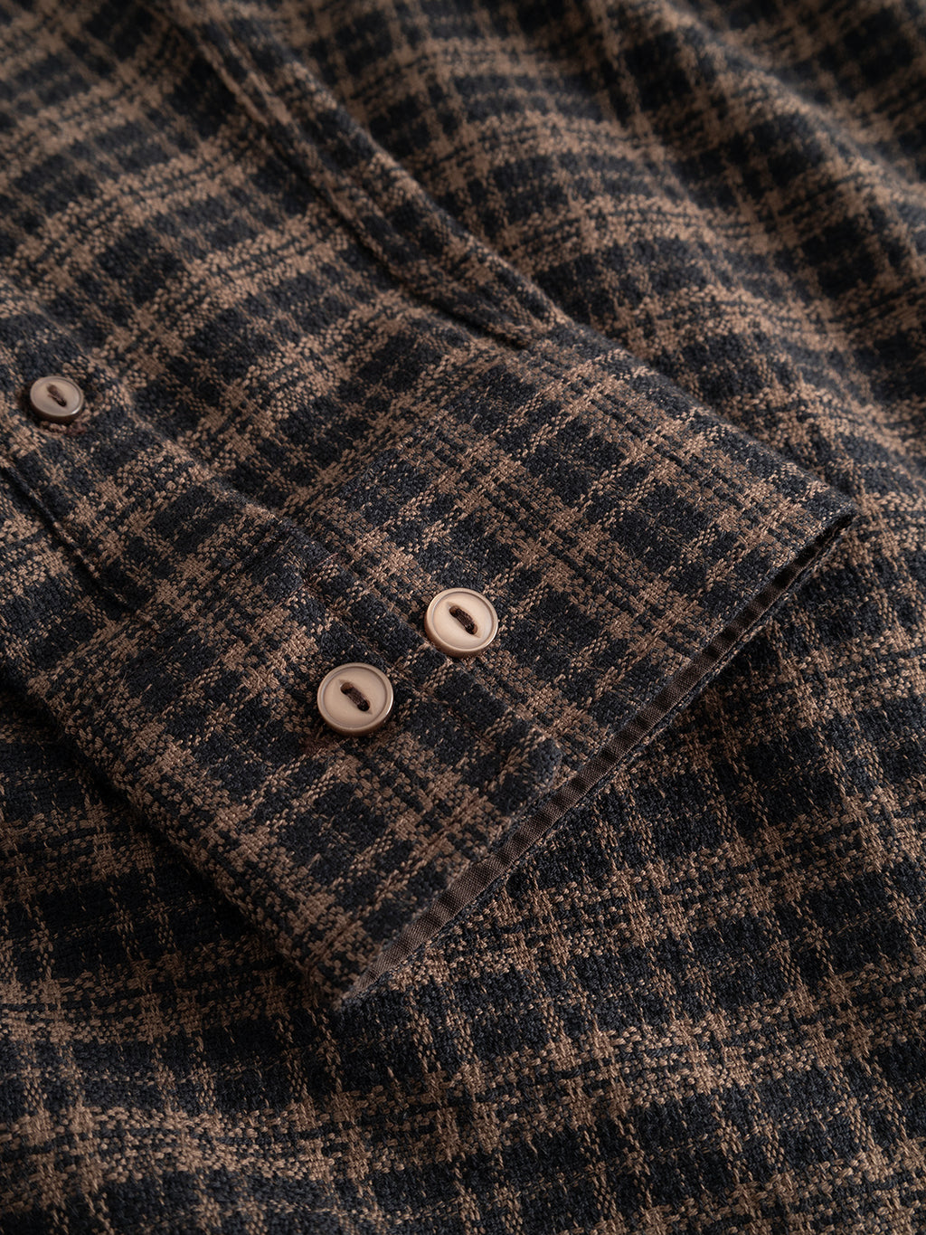 Close-up of the Gabba GABsven Reg TX2 LS Shirt in Brown Slate, highlighting the classic yarn-dyed checked texture of this regular-fit cotton shirt. The sleeve features two white buttons on the cuff and part of a buttoned placket in dark and light plaid tones.