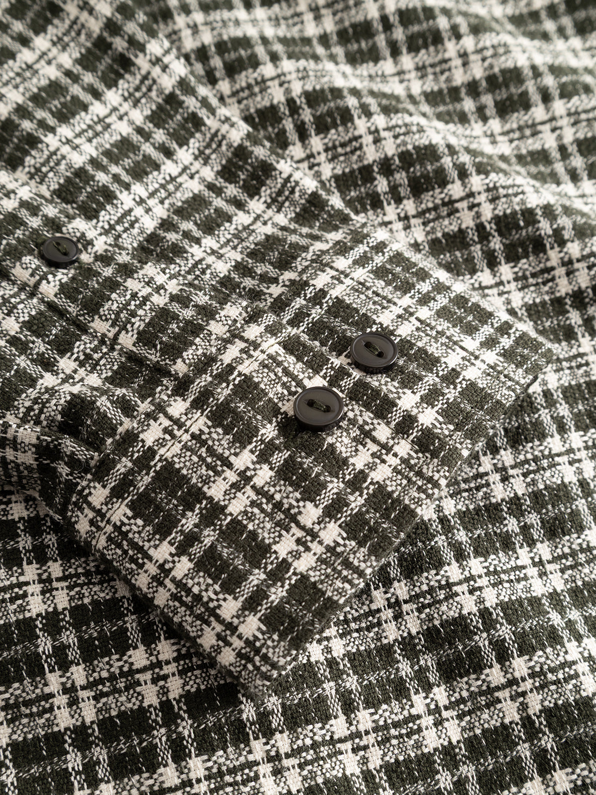 Close-up of the GABsven Reg TX2 LS Shirt - Forest Night by Gabba, featuring a black and white plaid yarn-dyed cotton sleeve with a checked texture and three black buttons on the cuff.