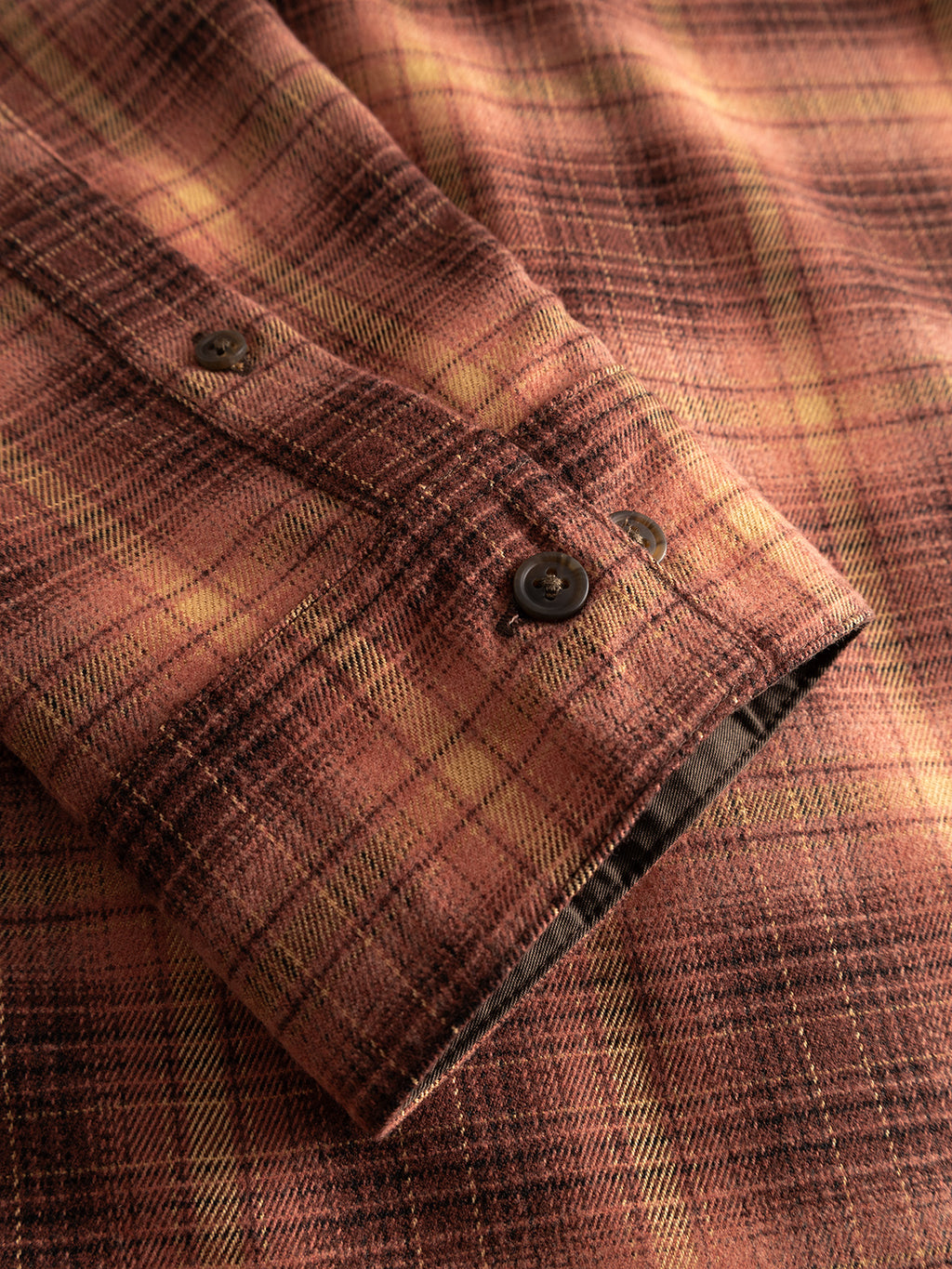A close-up of the GABsven Reg F1097 LS Shirt by Gabba in Brick Red showcases the shirt’s brown and yellow plaid sleeve, highlighting black buttons, detailed stitching on the cuff, and the checked texture of its regular fit design.