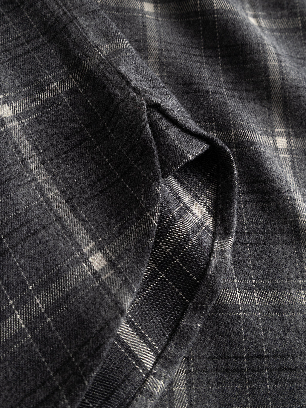 Close-up of the GABsven Reg F1097 LS Shirt - Night Sky by Gabba, featuring soft, dark gray flannel fabric with a lighter gray and white checked pattern, showcasing precise stitching and gentle folds—ideal for a regular-fit shirt.