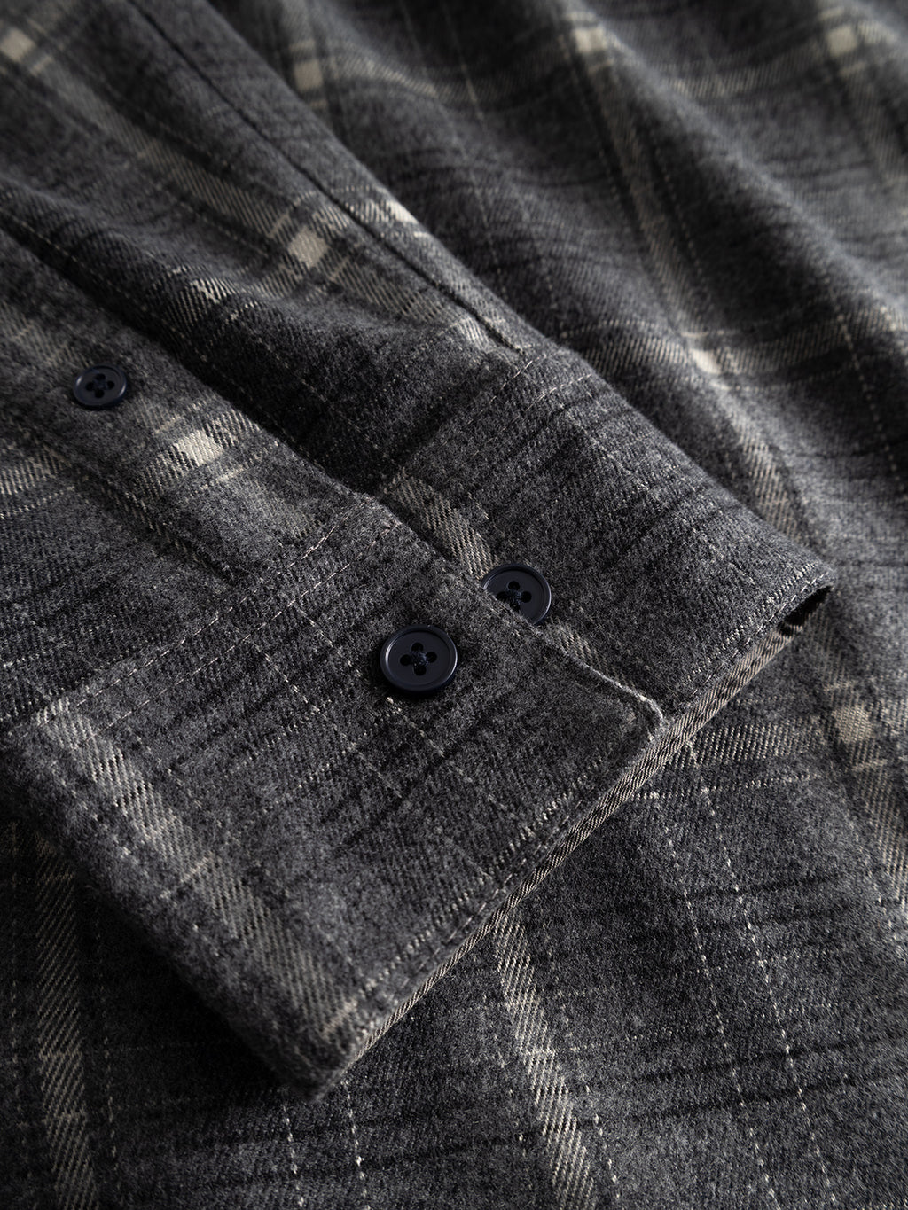 Close-up of the Gabba GABsven Reg F1097 LS Shirt - Night Sky sleeve, showcasing two black buttons on the cuff. The fabric displays a grey plaid pattern with intersecting light and dark lines, accentuating its checked texture.