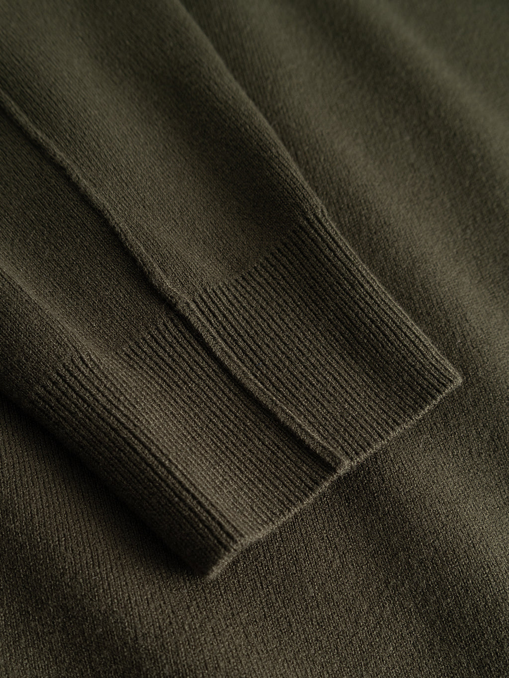 Close-up of the Gabba GABadriel O-Neck Lume LS Knit sweater in Forest Night, highlighting the ribbed cuff and soft textured fabric made from a mid-weight viscose blend in a dark olive green shade.