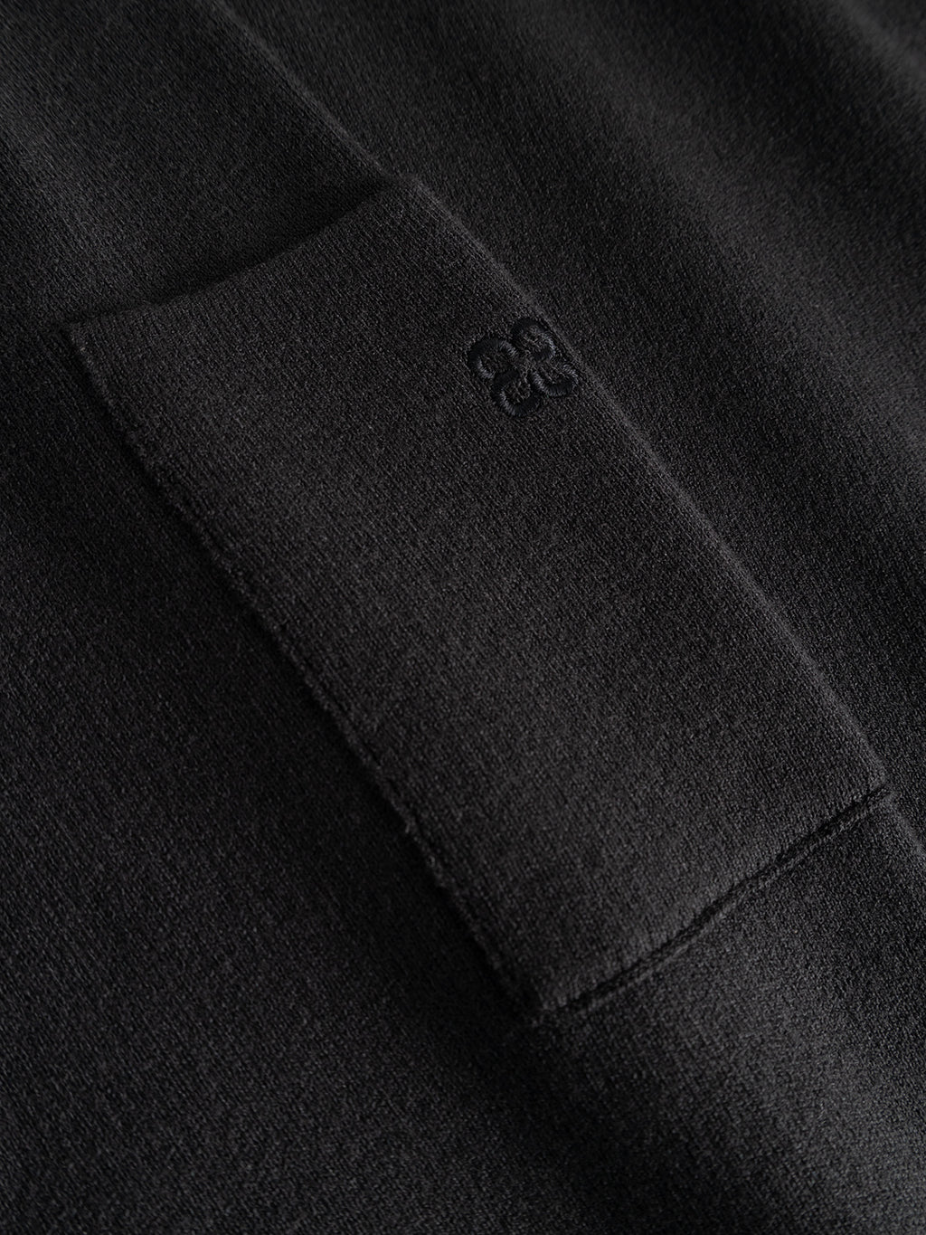 Close-up of the Gabba GABadriel O-Neck Lume LS Knit in Meteorite, a black viscose blend knit sweater featuring a rectangular pocket with a subtle embroidered logo near its top. The regular-fit design showcases a soft, slightly fuzzy texture.