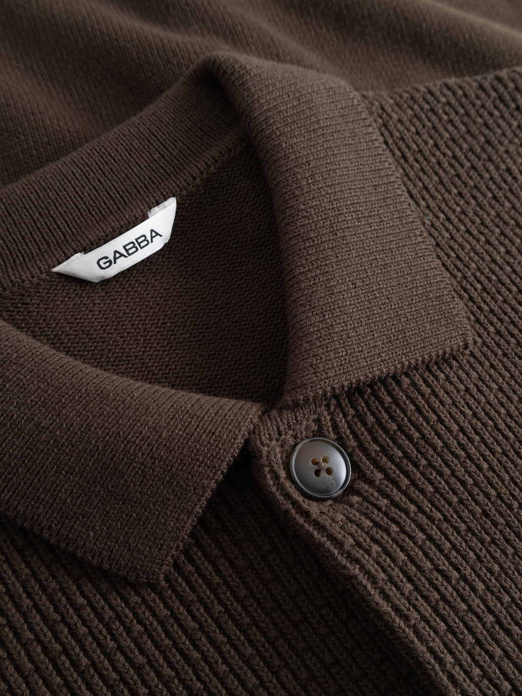 Close-up of a GABbenoit Cardi Fort LS Knit - Brown Slate, featuring a brown long-sleeved structured knit cardigan with a collared neckline and a single visible button.